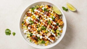Street corn chicken rice bowl topped with charred corn, cotija cheese, and lime crema