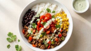 Ground Beef Burrito Bowl in a wide bowl with rice, beans, corn, and jalapeño cilantro sauce