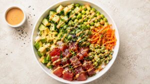 Wide angle shot of a finished ahi tuna poke bowl topped with avocado, edamame, and sesame seeds