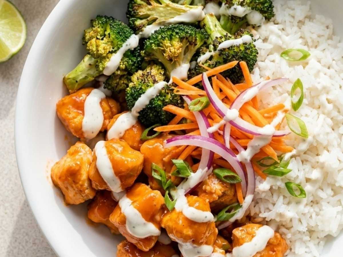 Close up of buffalo chicken rice bowl showing crispy chicken pieces coated in Frank's Red Hot sauce over rice