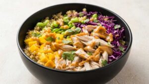 Easy Chicken Protein Bowl You'll Make on Repeat Chicken Protein Bowl with quinoa, chicken, mango, and peanut sauce