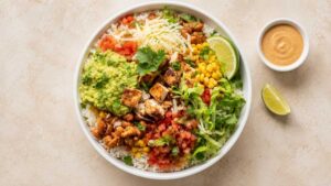 Wide angle shot of a finished chipotle chicken bowl with cilantro lime rice, pinto beans, and fresh toppings