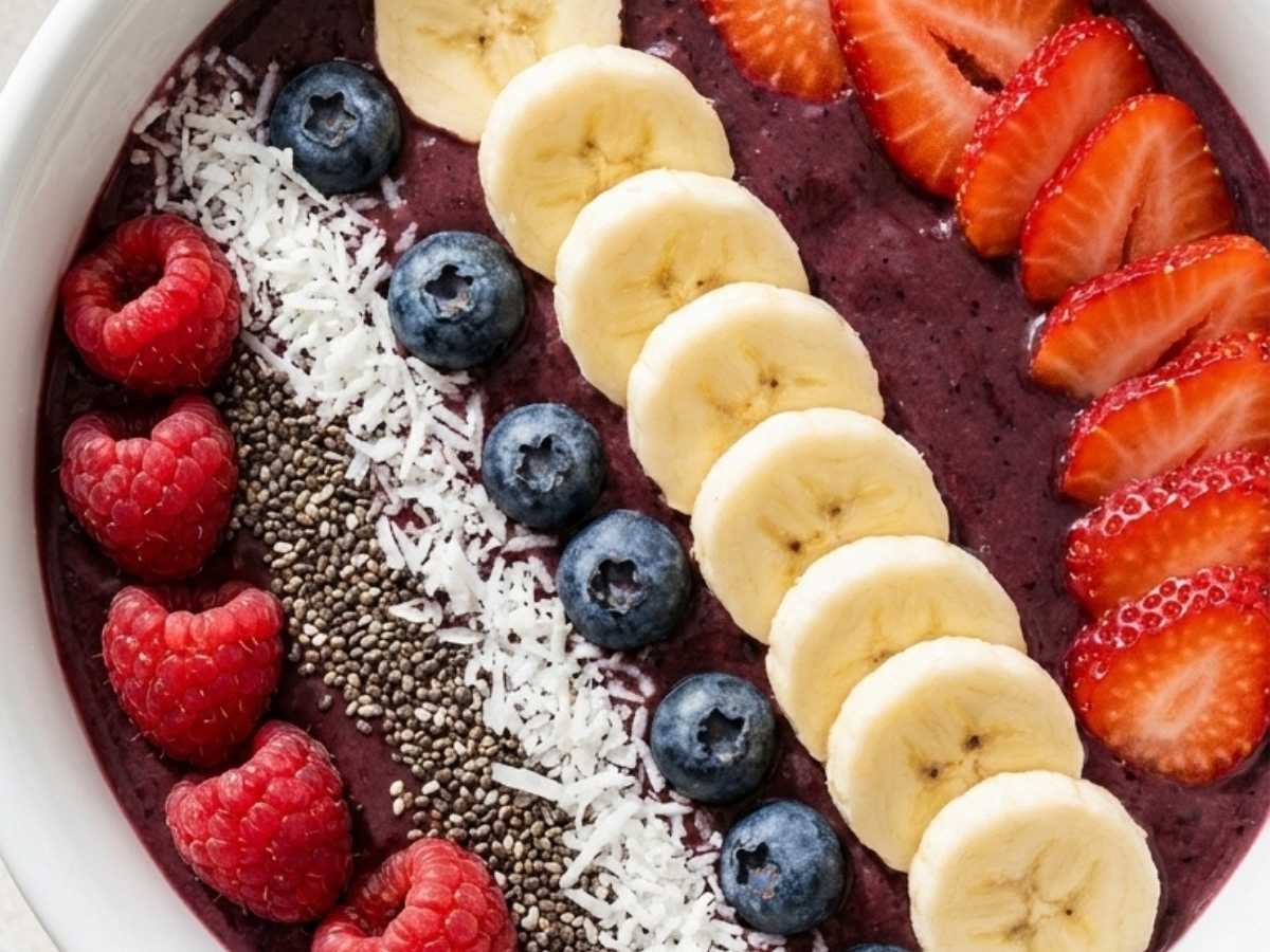 Close-up of a classic acai bowl showing the thick acai base topped with fresh berries and shredded coconut