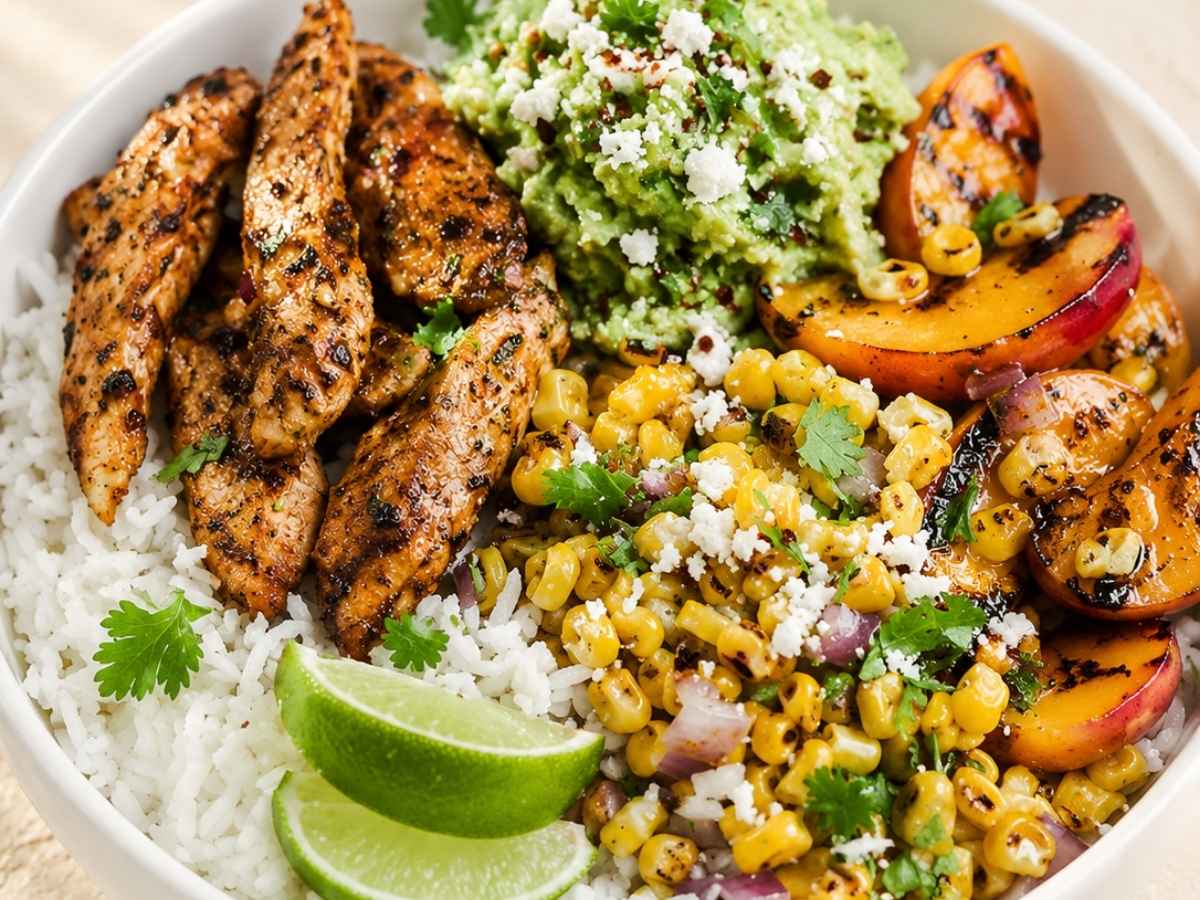Close up of a chicken taco bowl showing grilled peach slices, corn salsa, and crumbled cotija cheese