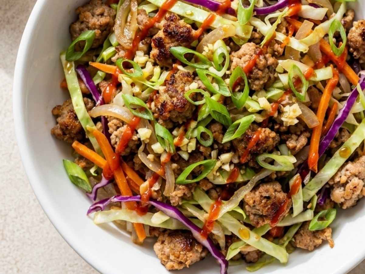 Close up of egg roll in a bowl showing tender pork, crisp cabbage, and scallions