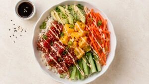 Wide angle view of a mango poke bowl topped with ahi tuna, avocado, mango, and cucumber