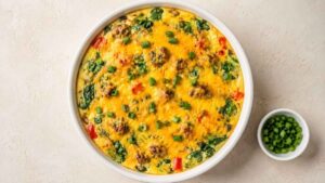 Baked egg bowl with turkey sausage, spinach, and melted cheddar in a white ramekin