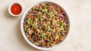 Wide angle shot of a high protein egg roll bowl with ground turkey, cabbage, and broccoli slaw in a white bowl