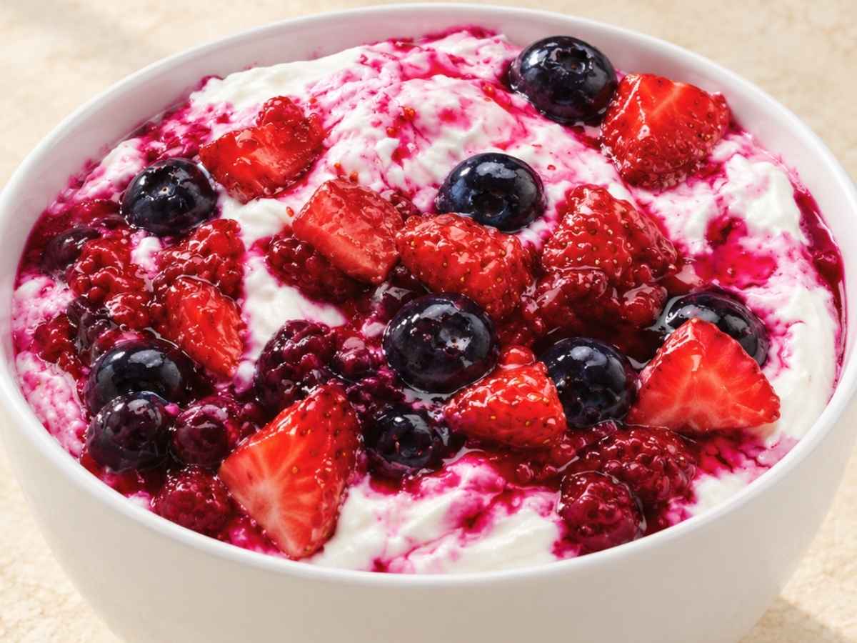 Closeup of creamy whipped Greek yogurt swirled with warm jammy berries in a bowl