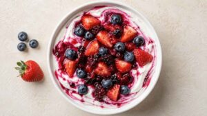 Wide angle shot of a low carb berry yogurt bowl topped with warm blueberries and strawberries