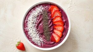 Finished protein smoothie bowl topped with granola and berries, wide overhead shot
