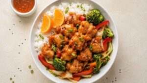 Wide angle view of orange chicken rice bowl with broccoli, bell peppers, and green onion