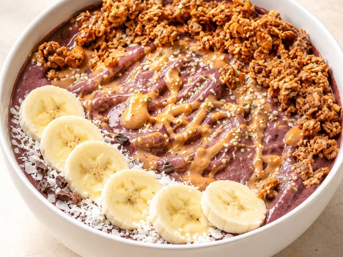 Close-up of a peanut butter acai bowl with a swirl of peanut butter, cacao nibs, and coconut flakes on top