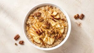 Wide angle view of peanut butter oatmeal breakfast bowl topped with chopped apples and pecans