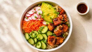 Salmon Protein Bowl Overhead shot of a salmon protein bowl with teriyaki salmon, brown rice, avocado, and crunchy veggies