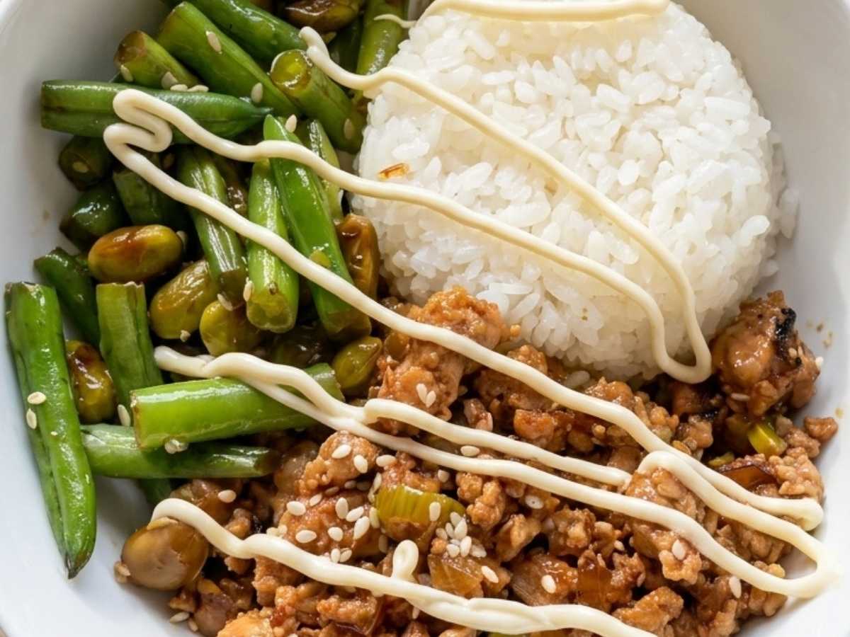 Close-up of sticky sesame chicken rice bowl topped with sesame seeds and a drizzle of Japanese mayo