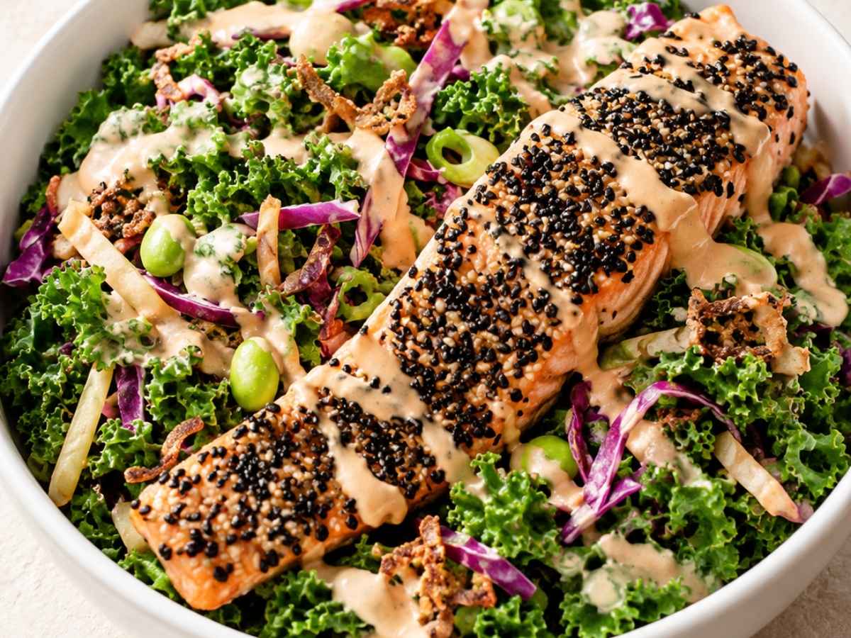 Close up of sesame crusted salmon flaking apart over black rice and miso tahini dressing