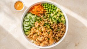 Shrimp poke bowl with sriracha shrimp, sushi rice and fresh veggies in a bowl