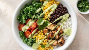 Southwest Burrito Bowl Southwest burrito bowl with chicken, rice, black beans, and avocado lime sauce in a meal prep container