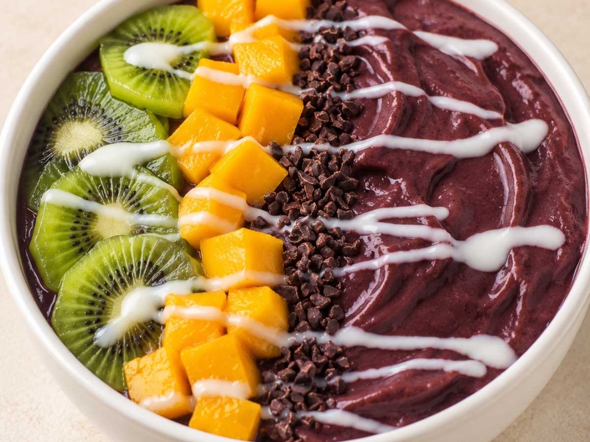 Close up of creamy tropical acai bowl with cacao nibs and coconut butter drizzle