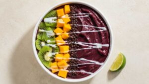 Spicy tropical acai bowl topped with kiwi, mango, and granola in a wide bowl