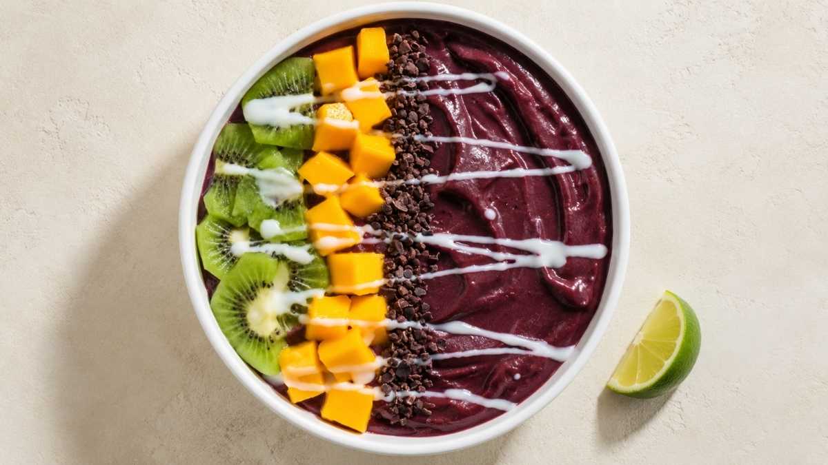 Spicy tropical acai bowl topped with kiwi, mango, and granola in a wide bowl
