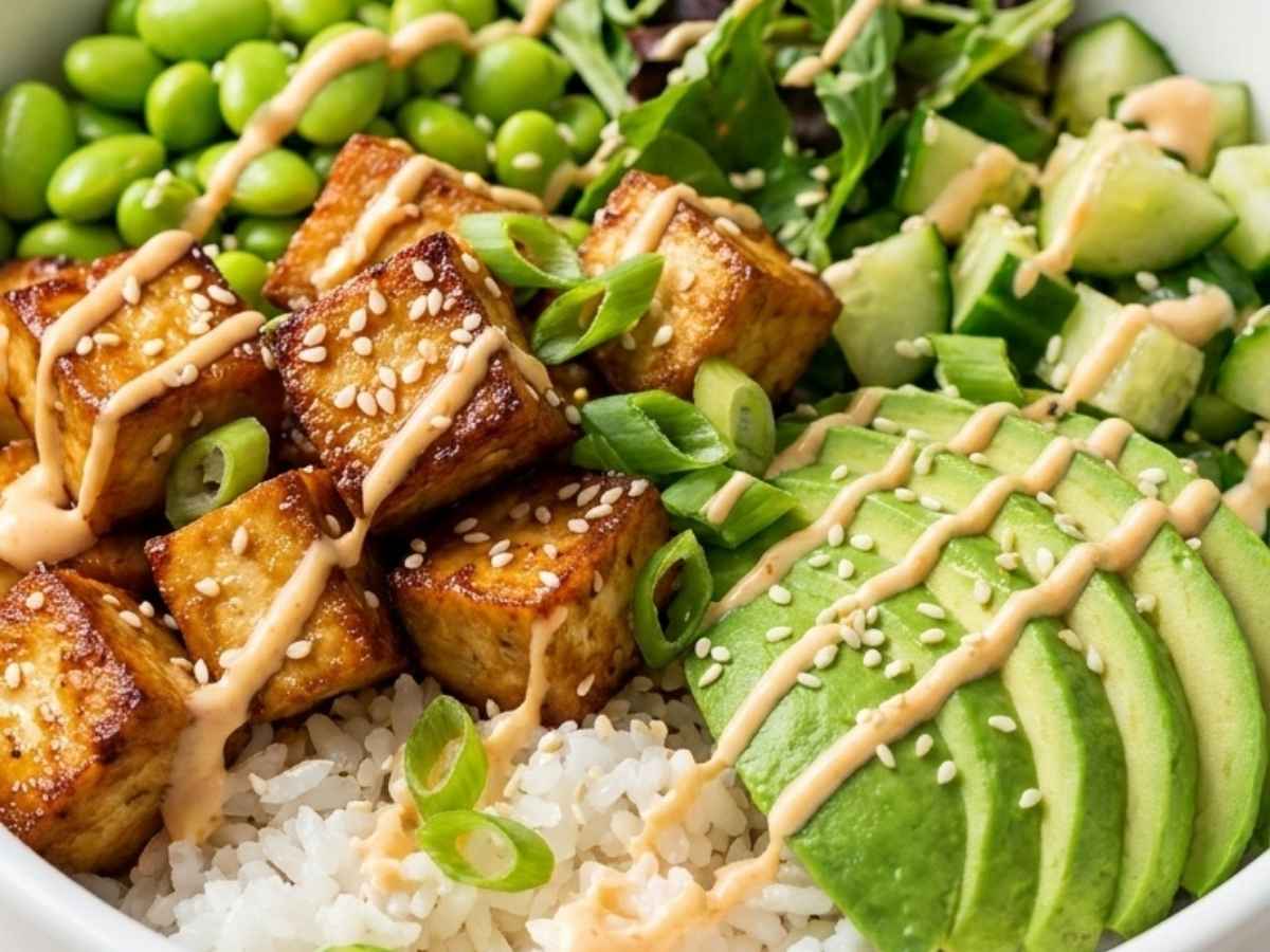 Closeup of crispy sesame tofu cubes over rice in a tofu poke bowl