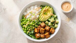 Tofu Poke Bowl Tofu poke bowl with crispy sesame tofu, brown rice, edamame, and avocado in a wide serving bowl