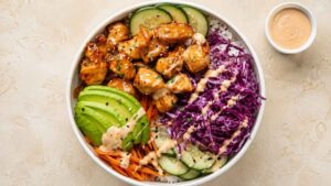 Bang bang chicken rice bowl topped with crispy air fried chicken, avocado, and sesame seeds