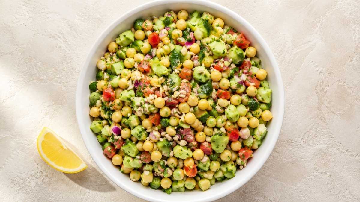 Chickpea avocado bowl with tomatoes, cucumber, and lemon dressing in a white bowl