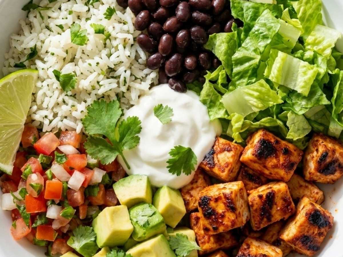 Close up of a chipotle chicken burrito bowl topped with avocado and corn salsa