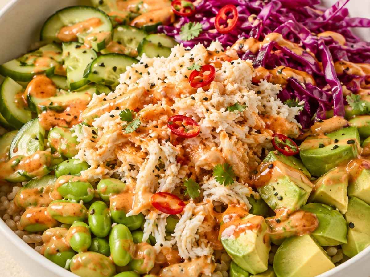 Close-up of a crab sushi bowl drizzled with creamy chilli dressing and fresh coriander