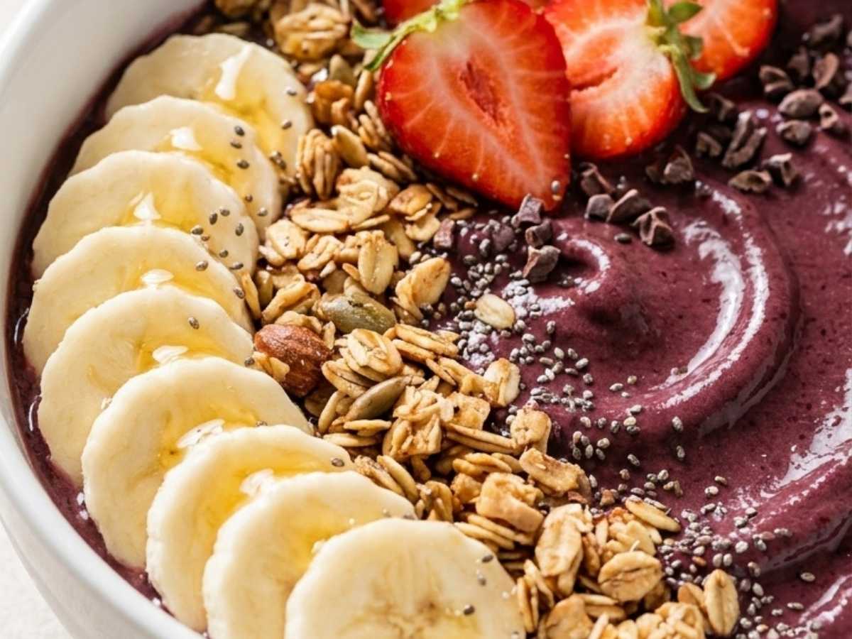 Closeup of a creamy high protein acai bowl with chia seeds, coconut flakes, and a honey drizzle