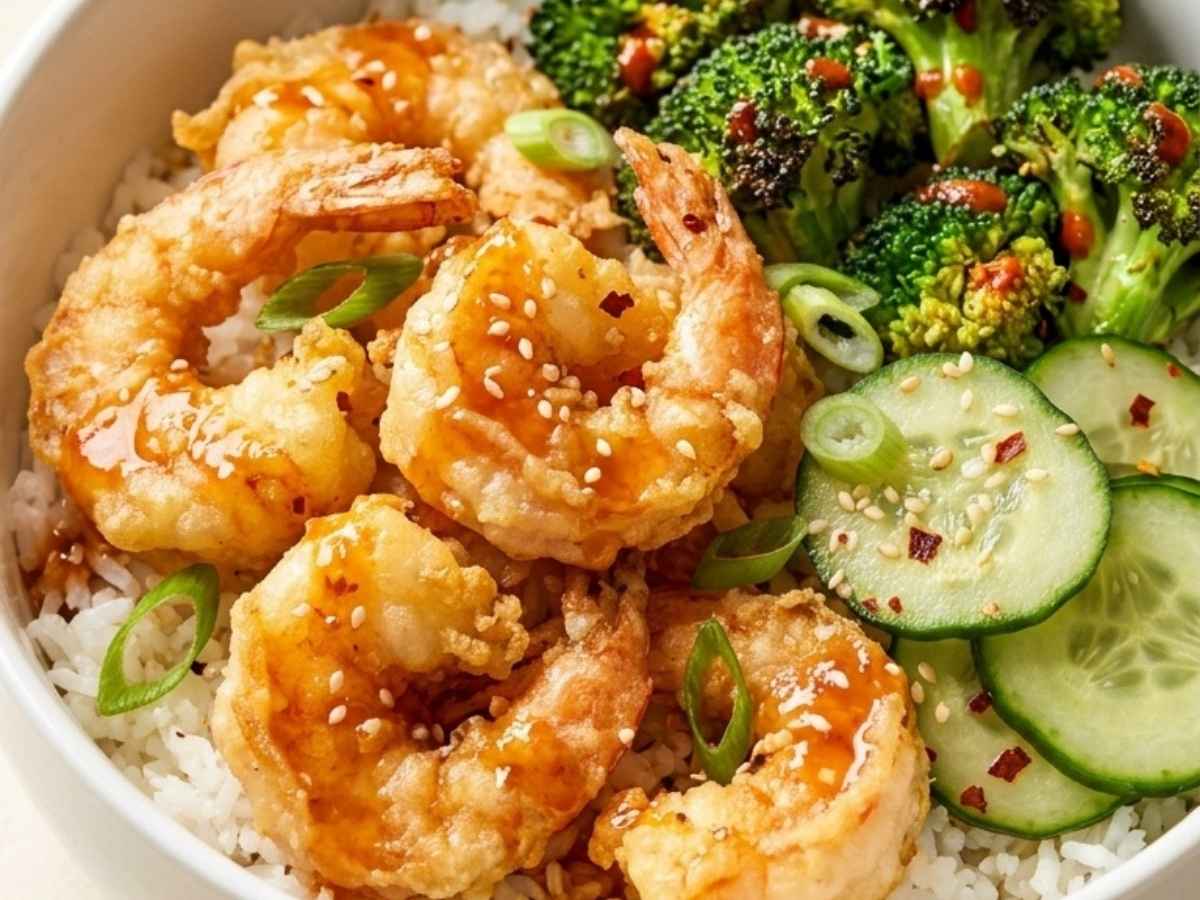 Close-up of crispy tempura shrimp drizzled with sweet heat sauce over rice