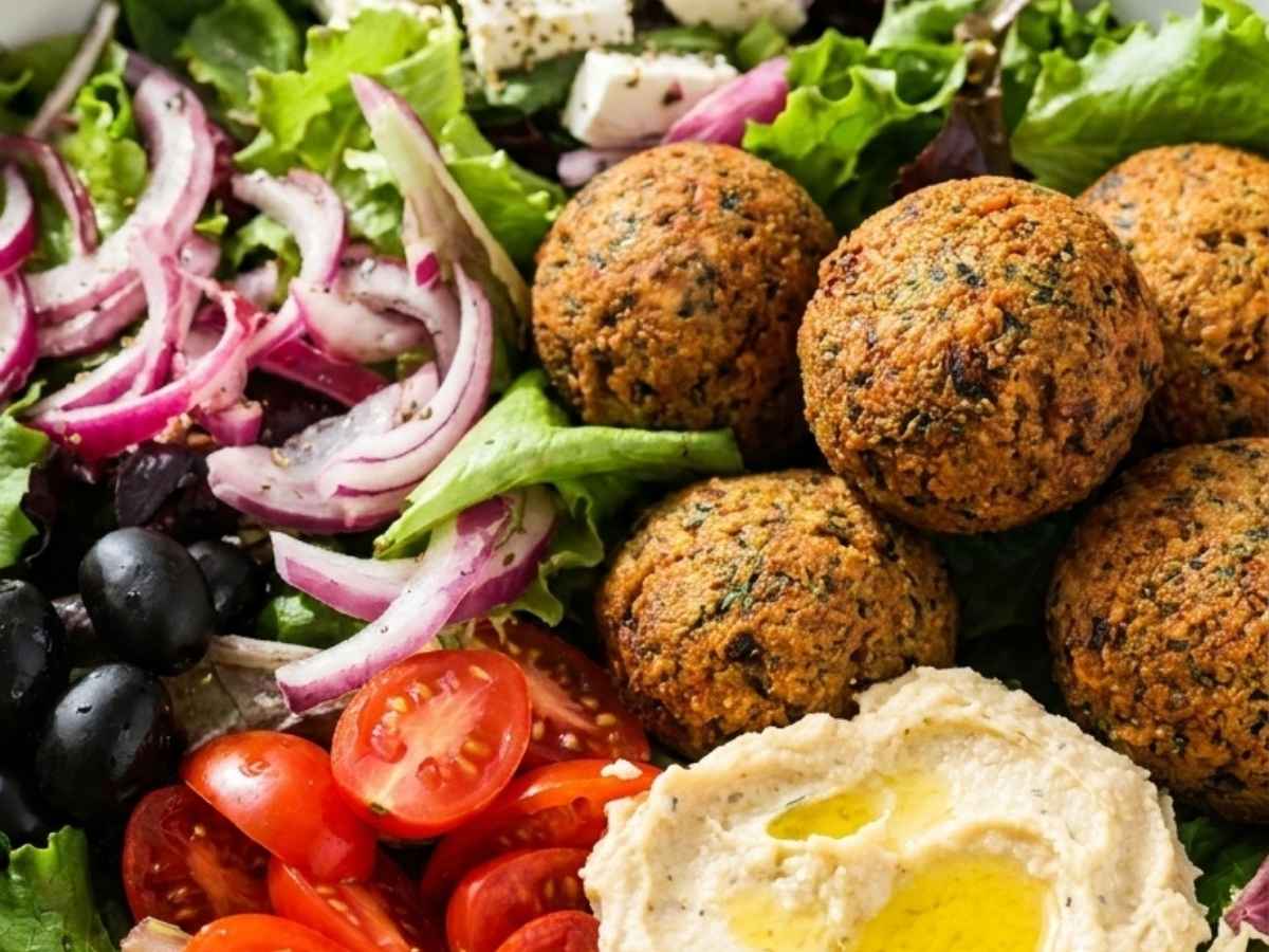 Close up of a falafel salad bowl showing crispy falafel, feta cheese, and lemon vinaigrette