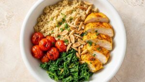 Healthy Chicken Quinoa Bowl Wide angle of a finished Healthy Chicken Quinoa Bowl with charred kale, blistered tomatoes, sliced chicken and toasted almonds