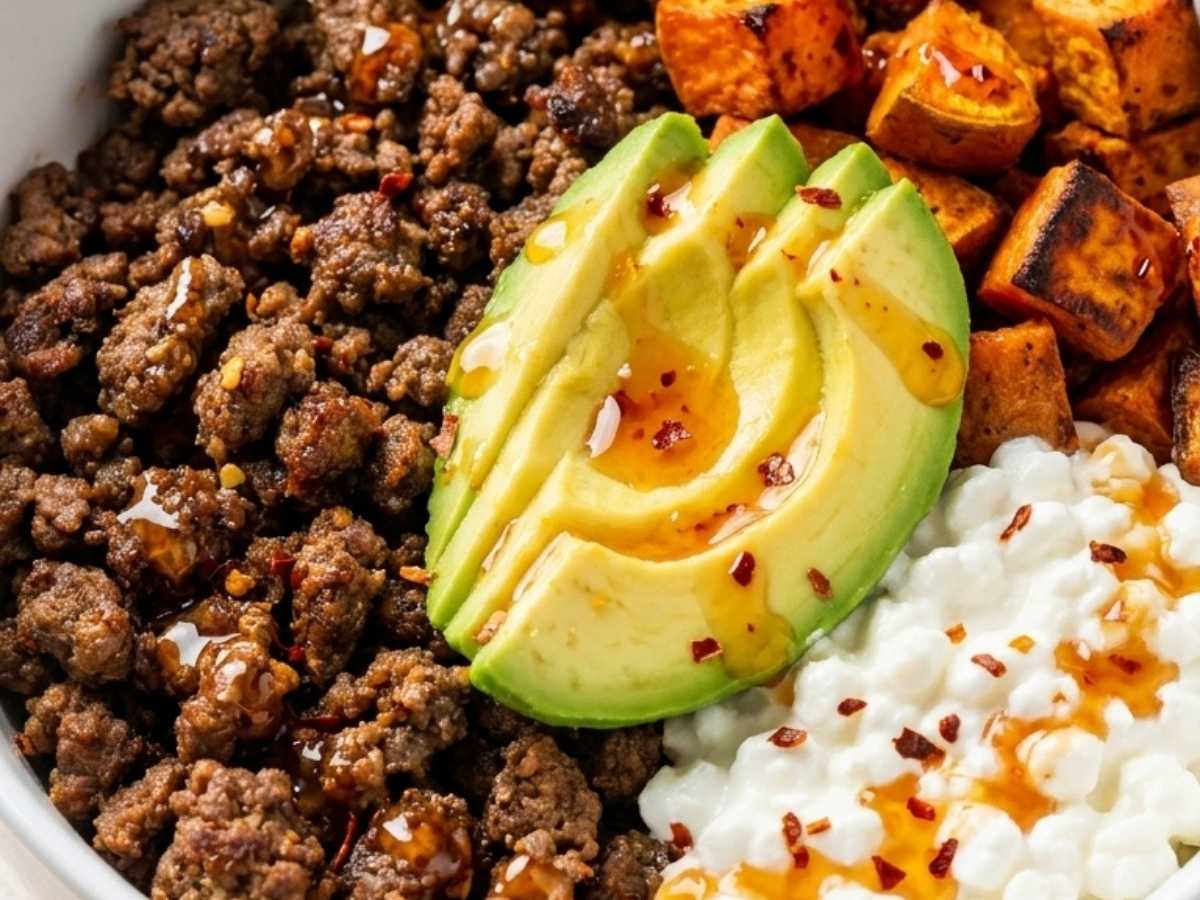 Close up of a high protein beef bowl showing caramelized sweet potatoes, seasoned beef, and hot honey drizzle