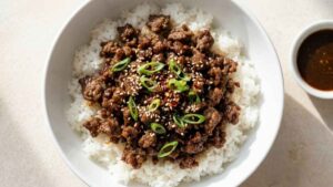 Korean Beef Rice Bowl Korean beef rice bowl with sweet soy glazed ground beef, rice, and green onions in a wide overhead shot