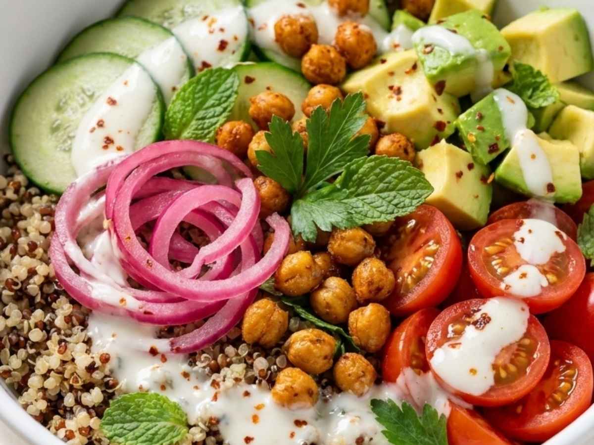 Closeup of Mediterranean quinoa bowl drizzled with garlic yogurt sauce and Aleppo pepper