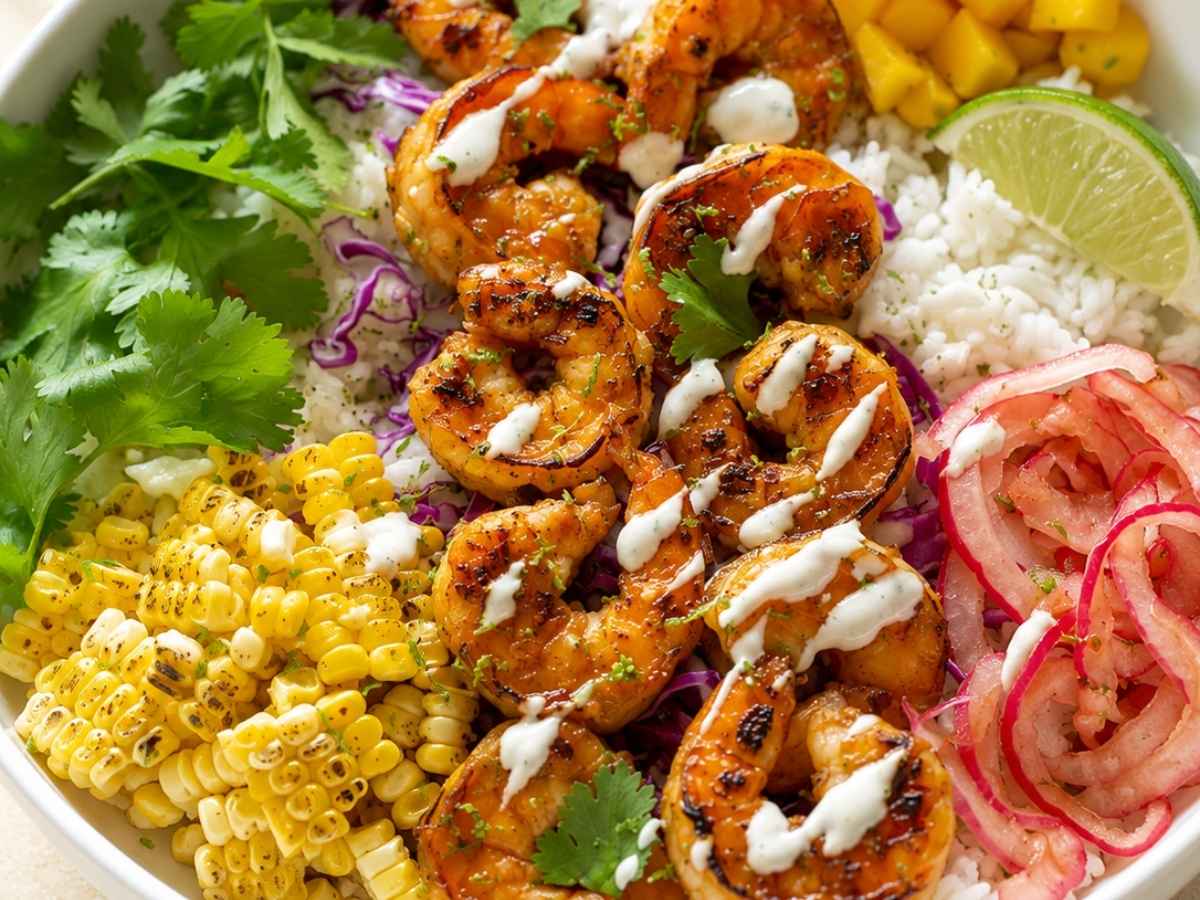 Close up of shrimp taco bowl topped with cilantro lime crema and pickled onions