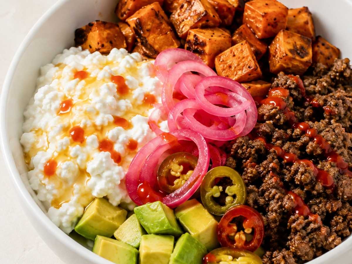 Close up of sweet potato protein bowl showing hot honey drizzle over cottage cheese and avocado