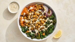 Sweet Potato Chickpea Buddha Bowl Wide shot of a sweet potato chickpea buddha bowl with roasted sweet potatoes, crispy chickpeas, kale, and maple tahini sauce